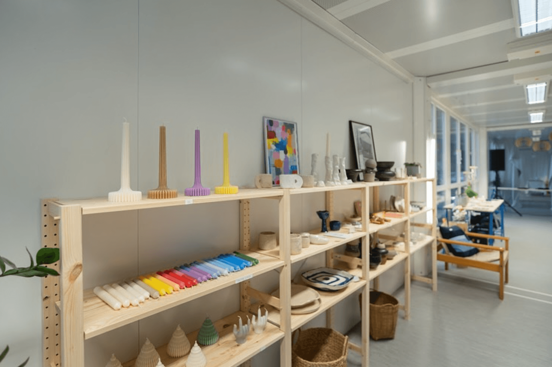 Kerzen, Keramik und andere Kunst stehen und liegen auf Holzregalen in einem Laden