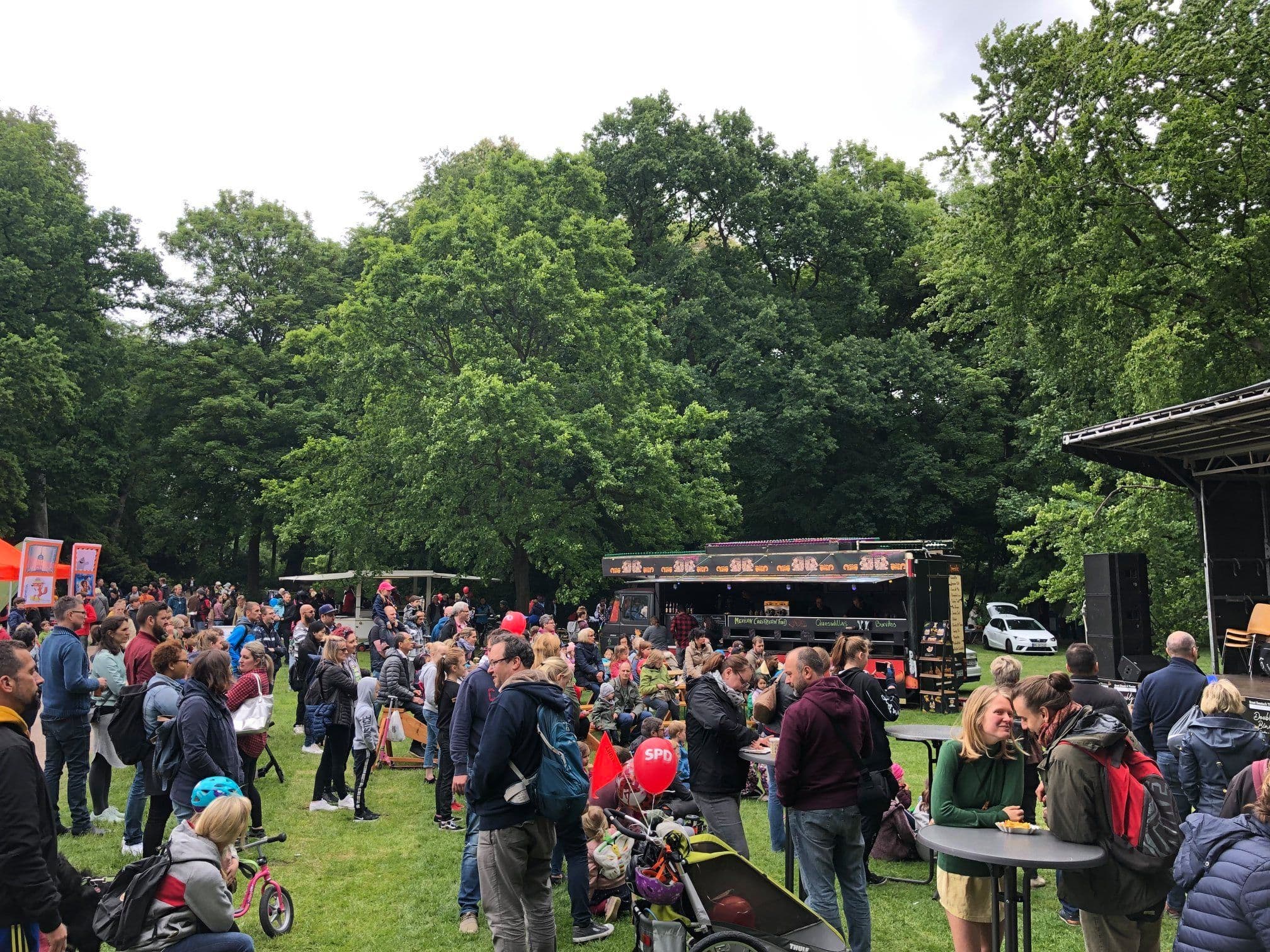 Personen stehen auf einer Wiese bei einem Sommerfest.