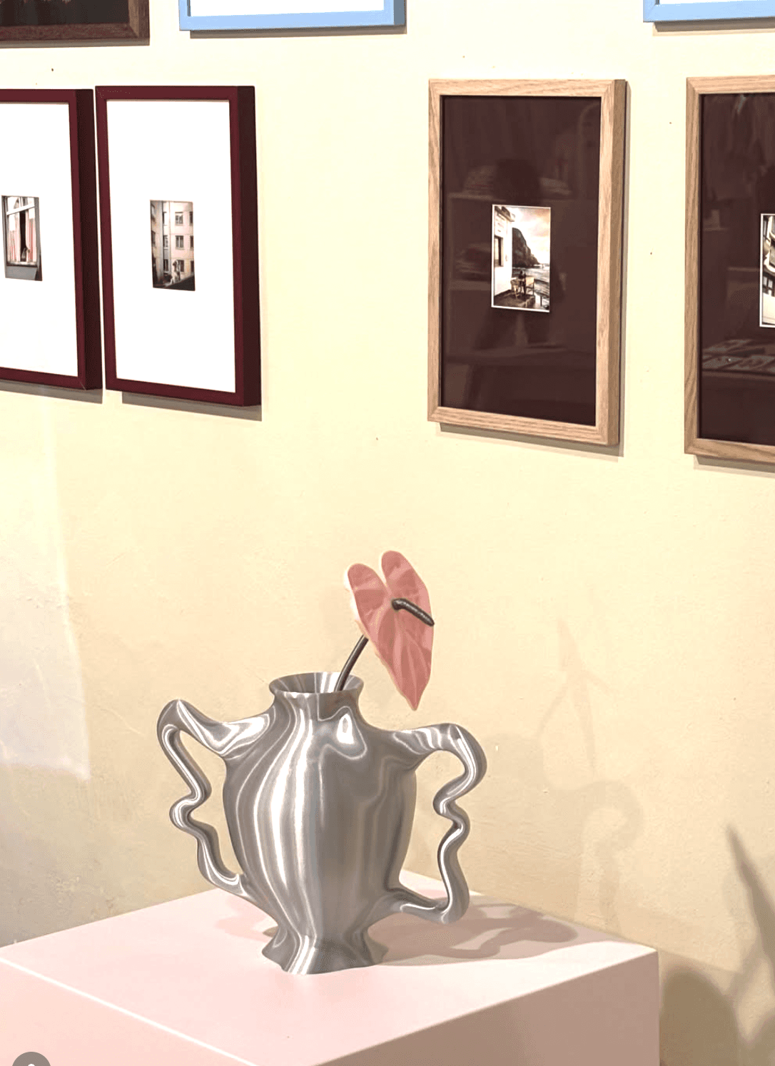 Eine Vase mit einer Blüte steht vor einer Bilderwand