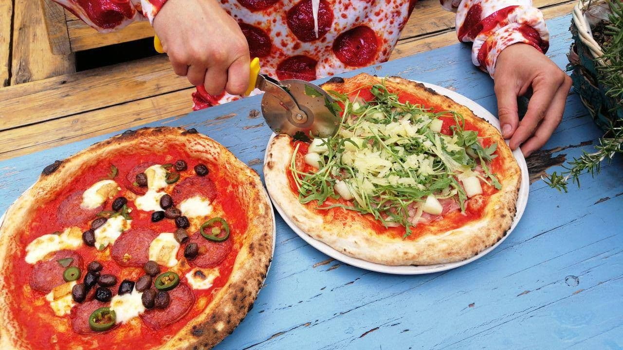 Person schneidet eine Pizza