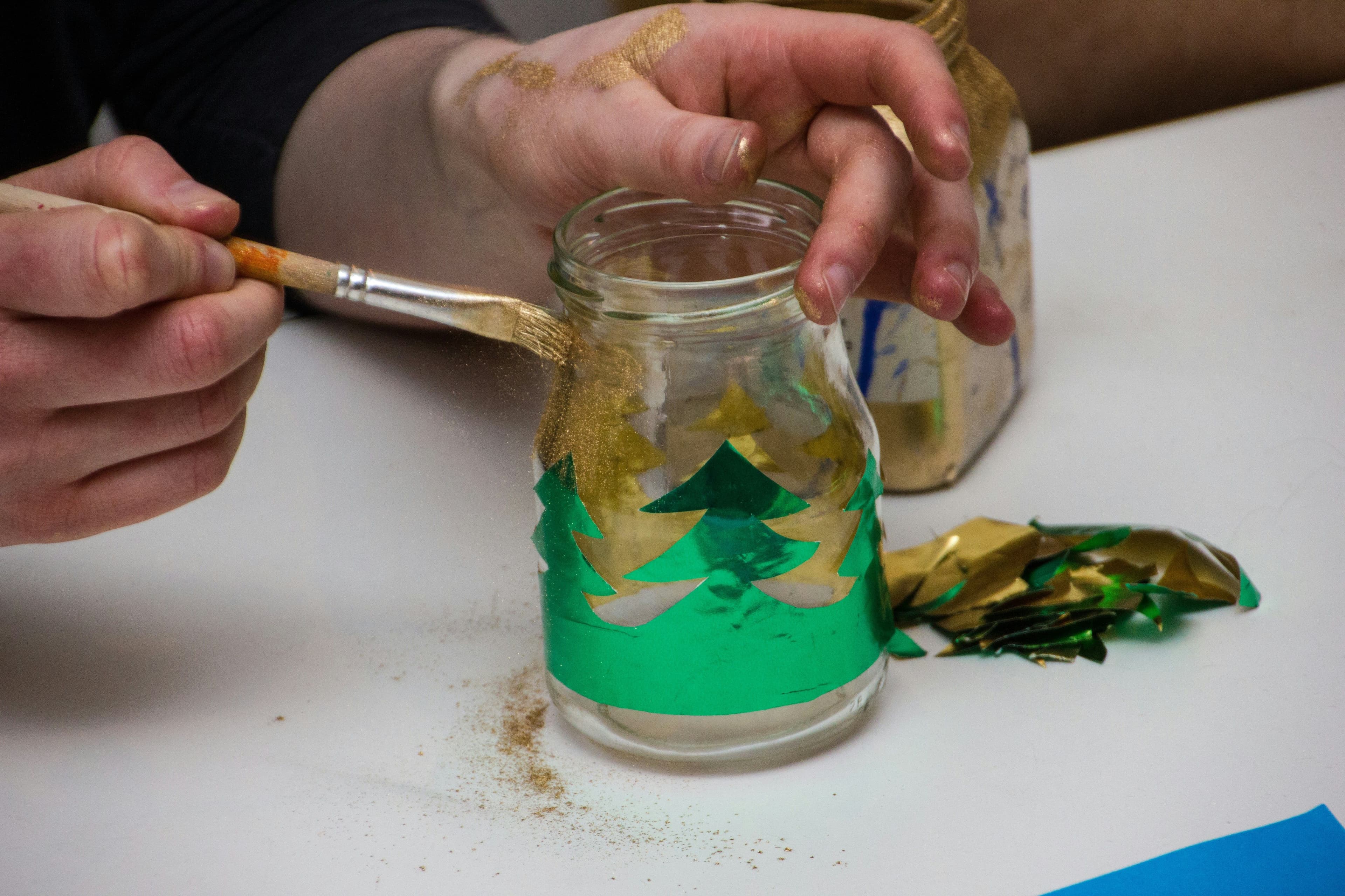 Nahaufnahme von einem Glas, welches von einer Person weihnachtlich bemalt wird.