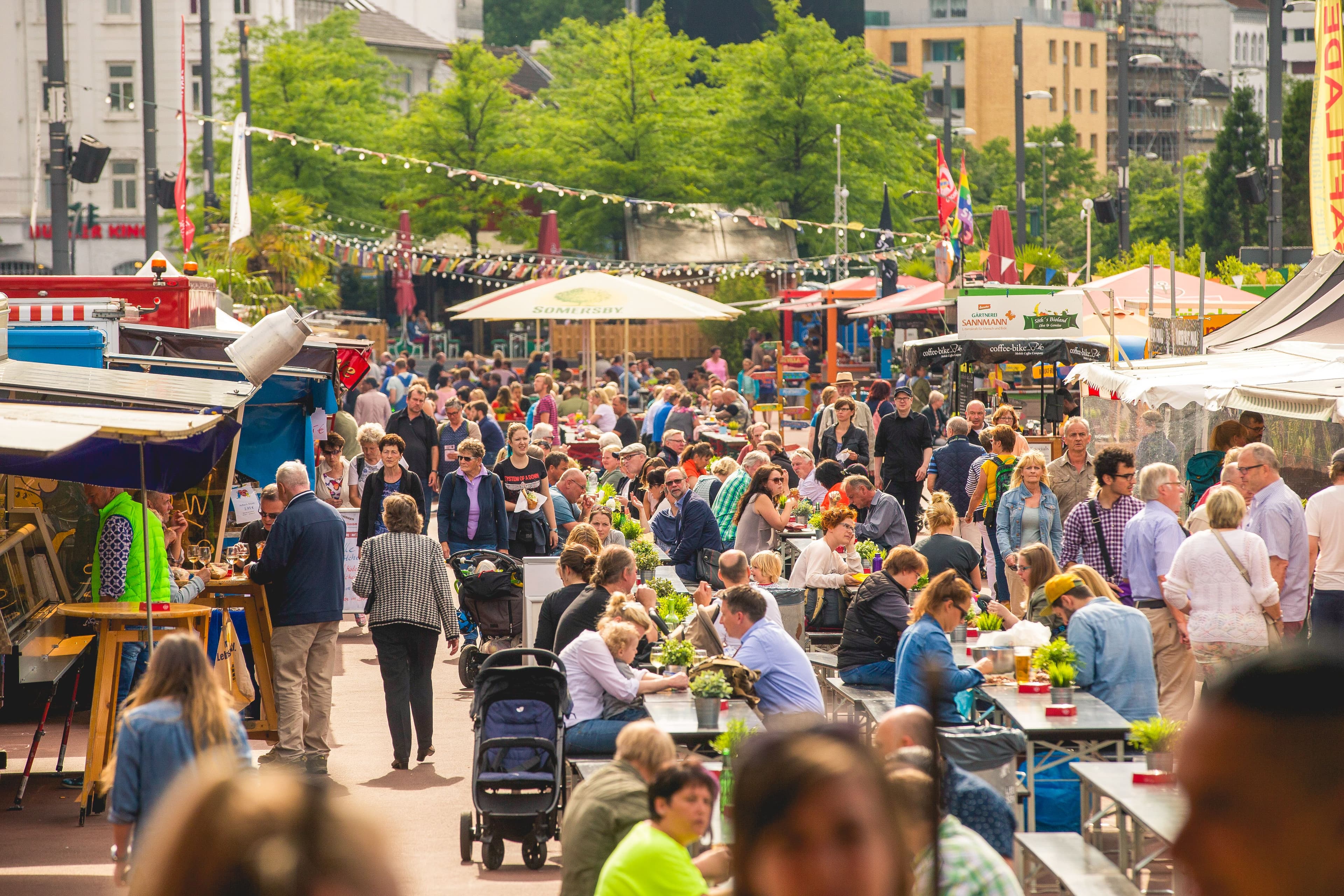 Personen sitzen an Tischen auf dem Nachtmarkt auf dem Spielbudenplatz