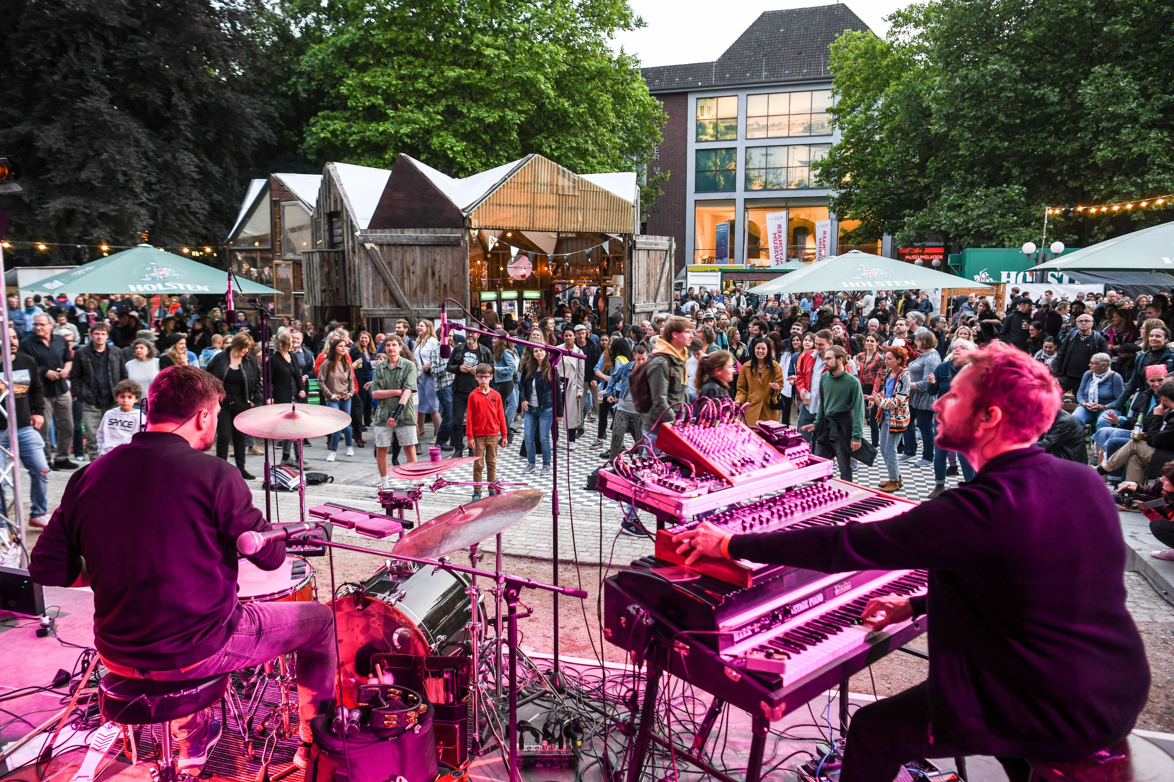 Eine Band spielt auf einer Bühne und davor stehen viele Menschen