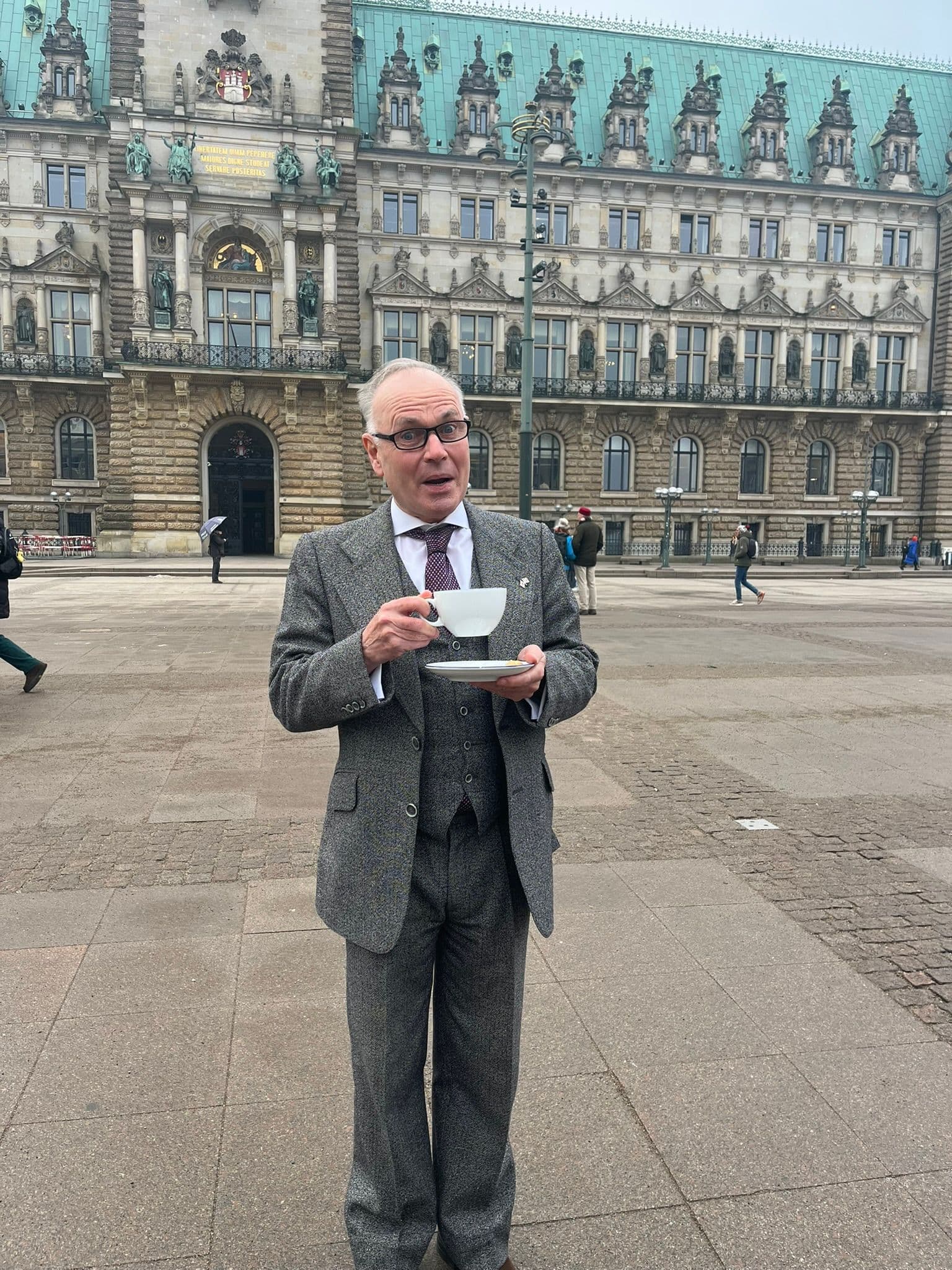 Mark Lyndon steht mit einer Tasse Tee vorm Hamburger Rathaus