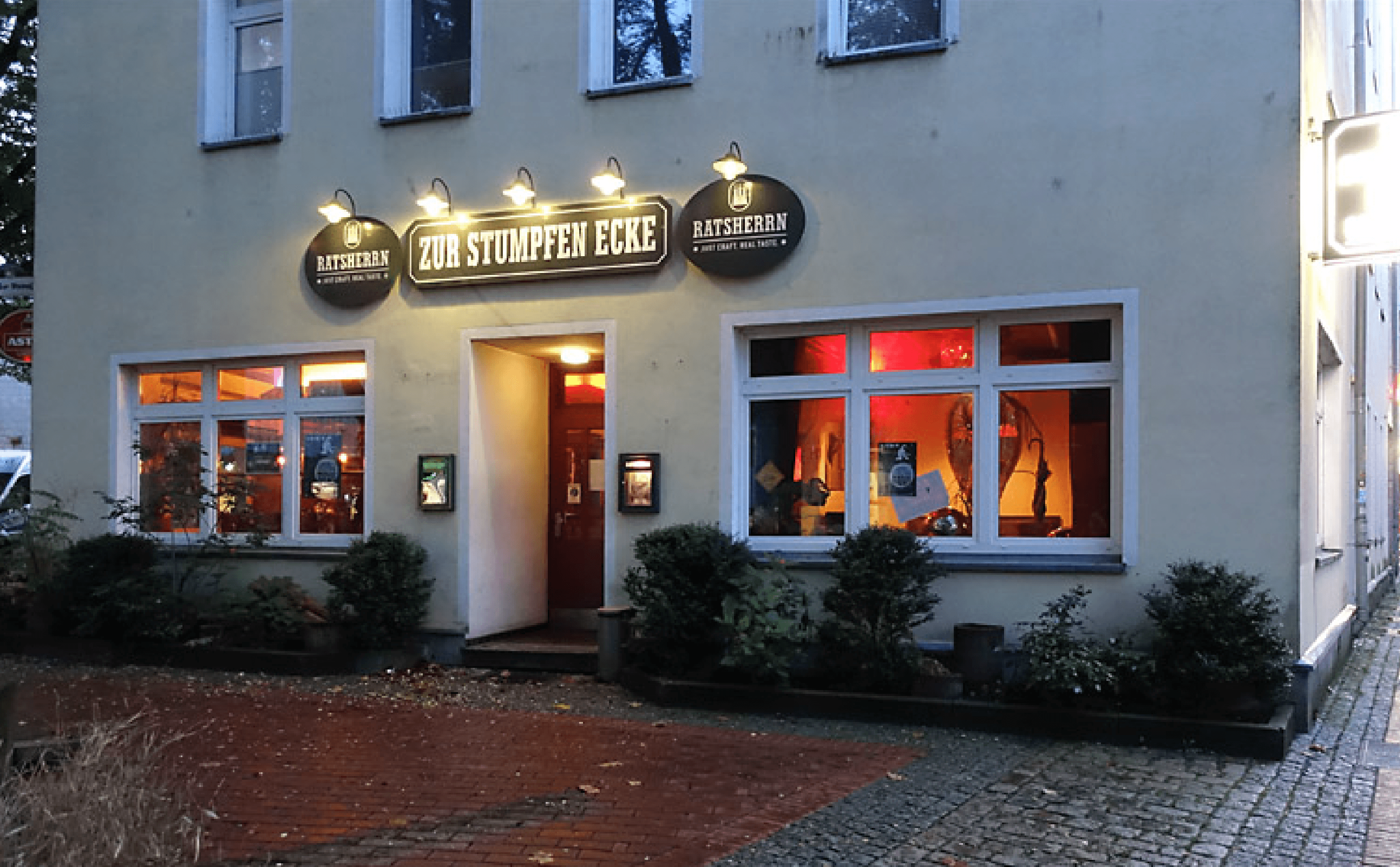 Fassade der Kneipe "Zur Stumpfen Ecke" ist mit beleuchtetem Eingang zu sehen.
