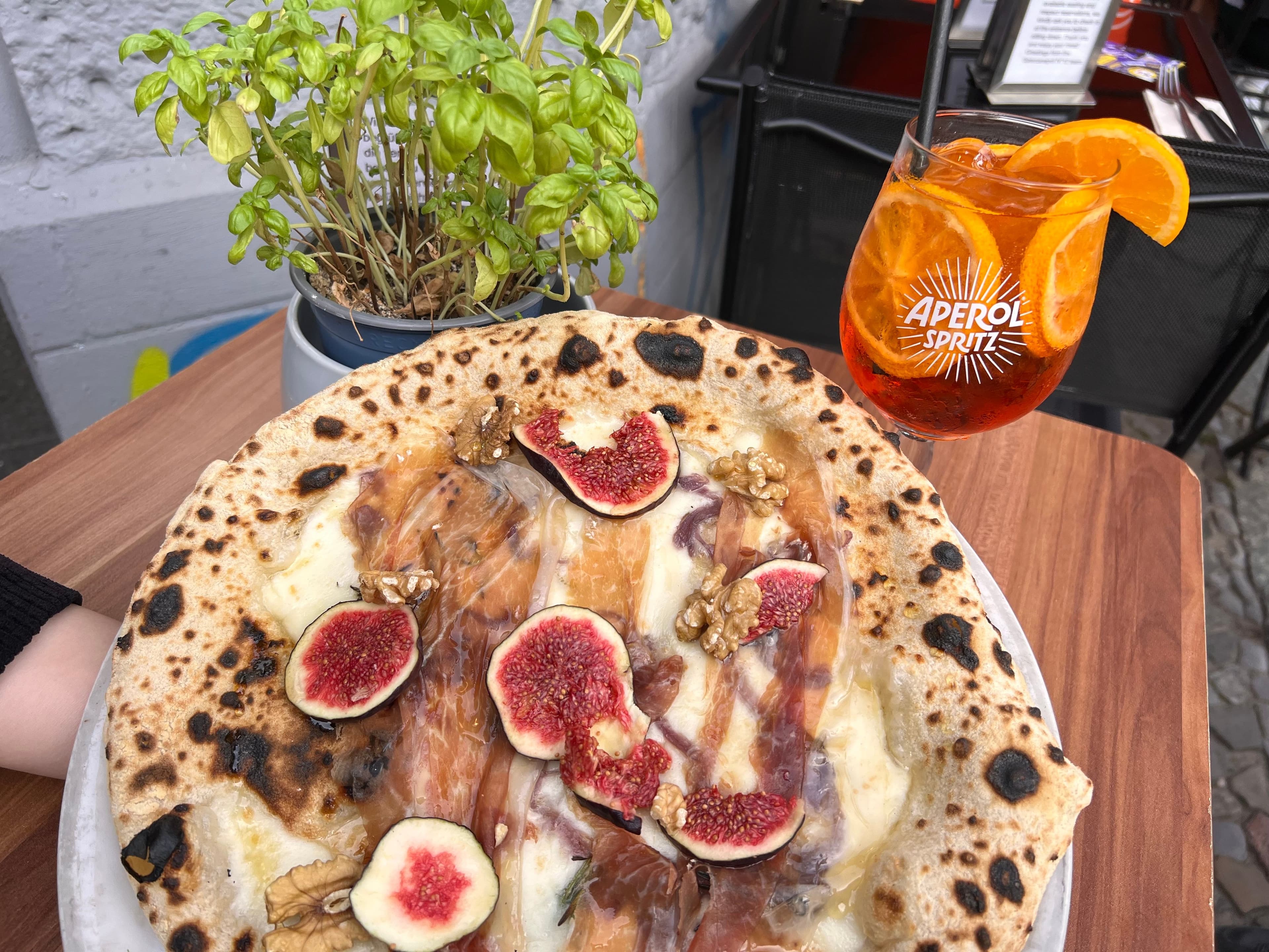 Eine Pizza belegt mit Feigen und ein Glas Aperol Spritz