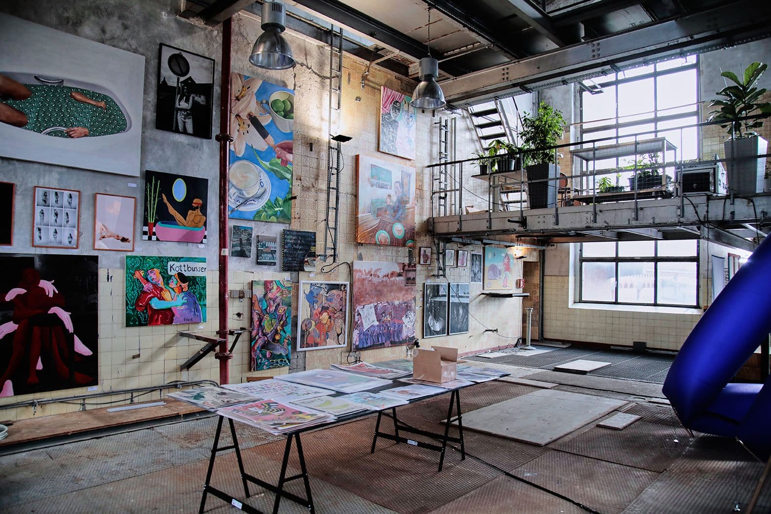 Kunstwerke sind in einem Loft an der Wand und auf Tischen ausgestellt