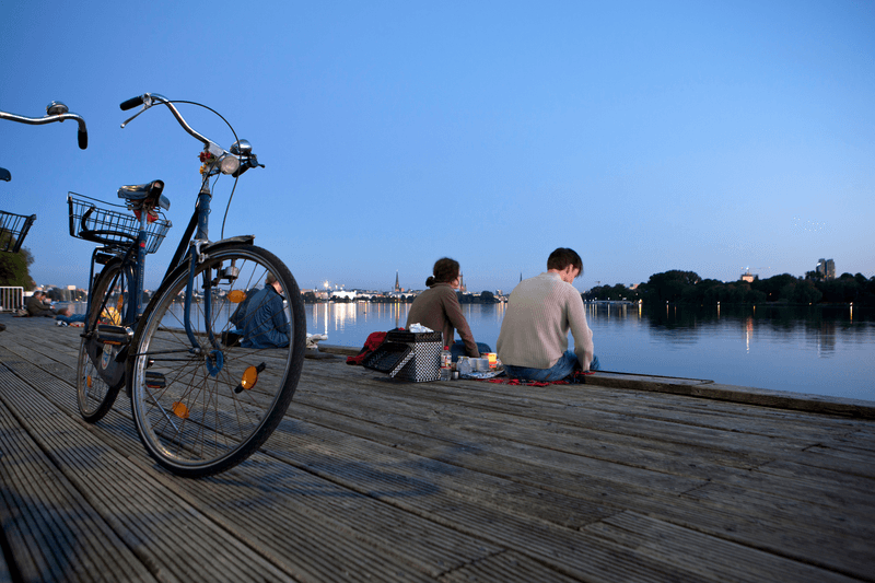Menschen sitzen an der Außenalster mit ihren Rädern