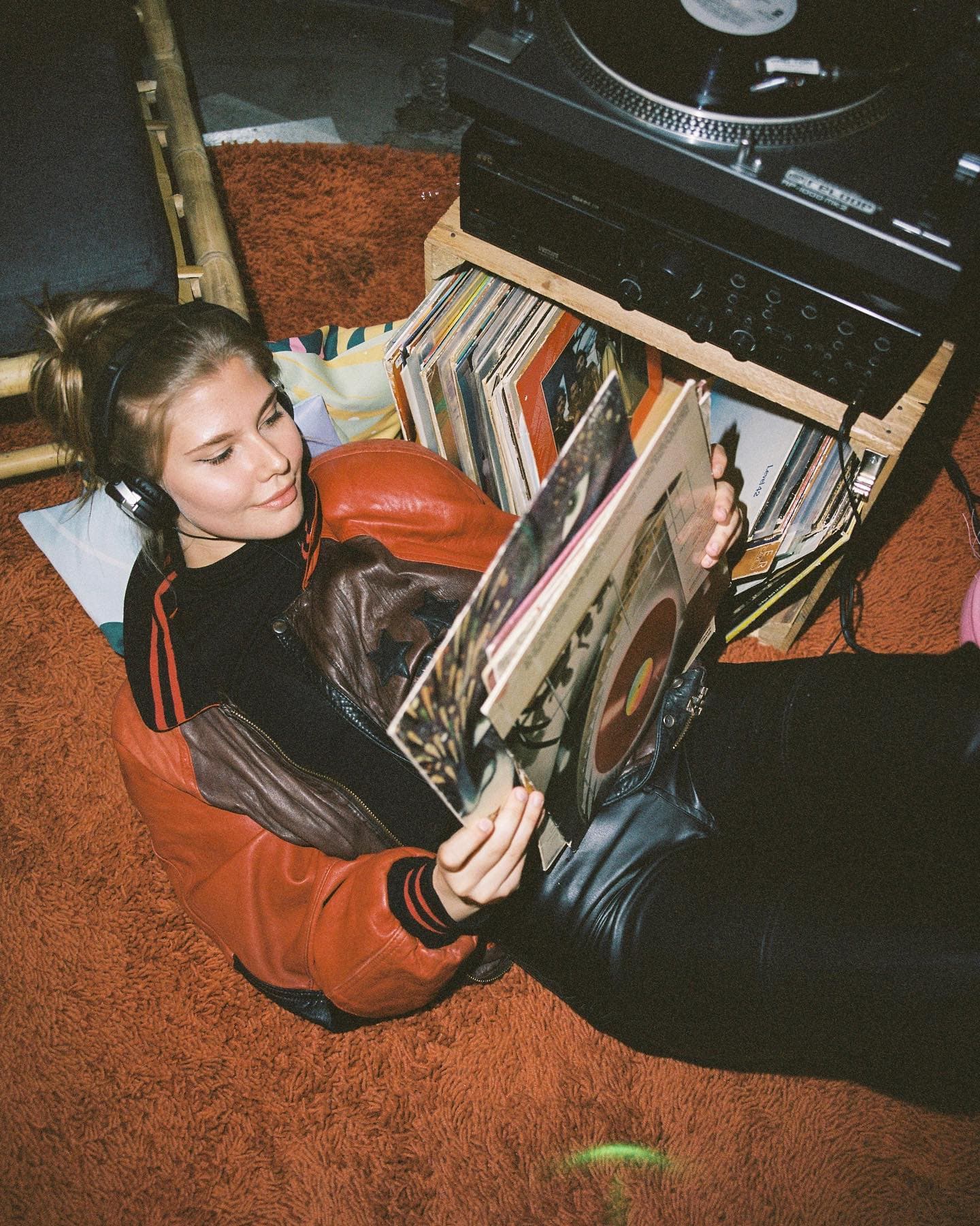 Eine Frau liegt auf dem Boden und schaut sich Schallplatten an