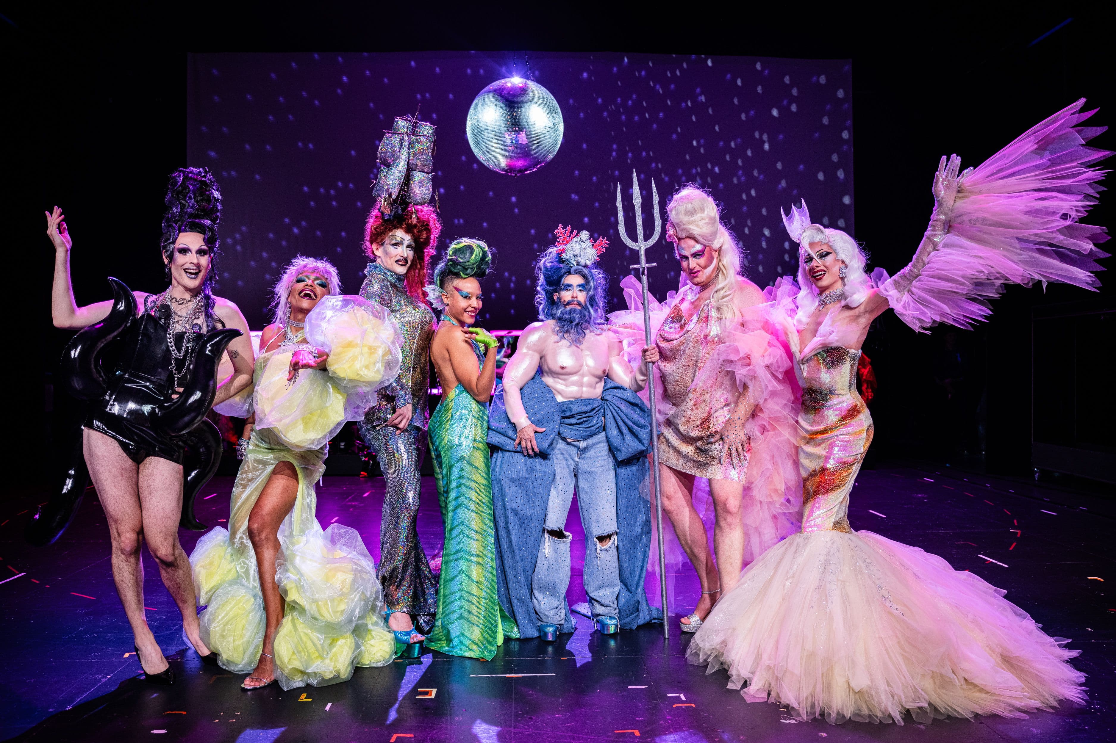 Buntes Ensemble in Drag-Outfits auf der Bühne