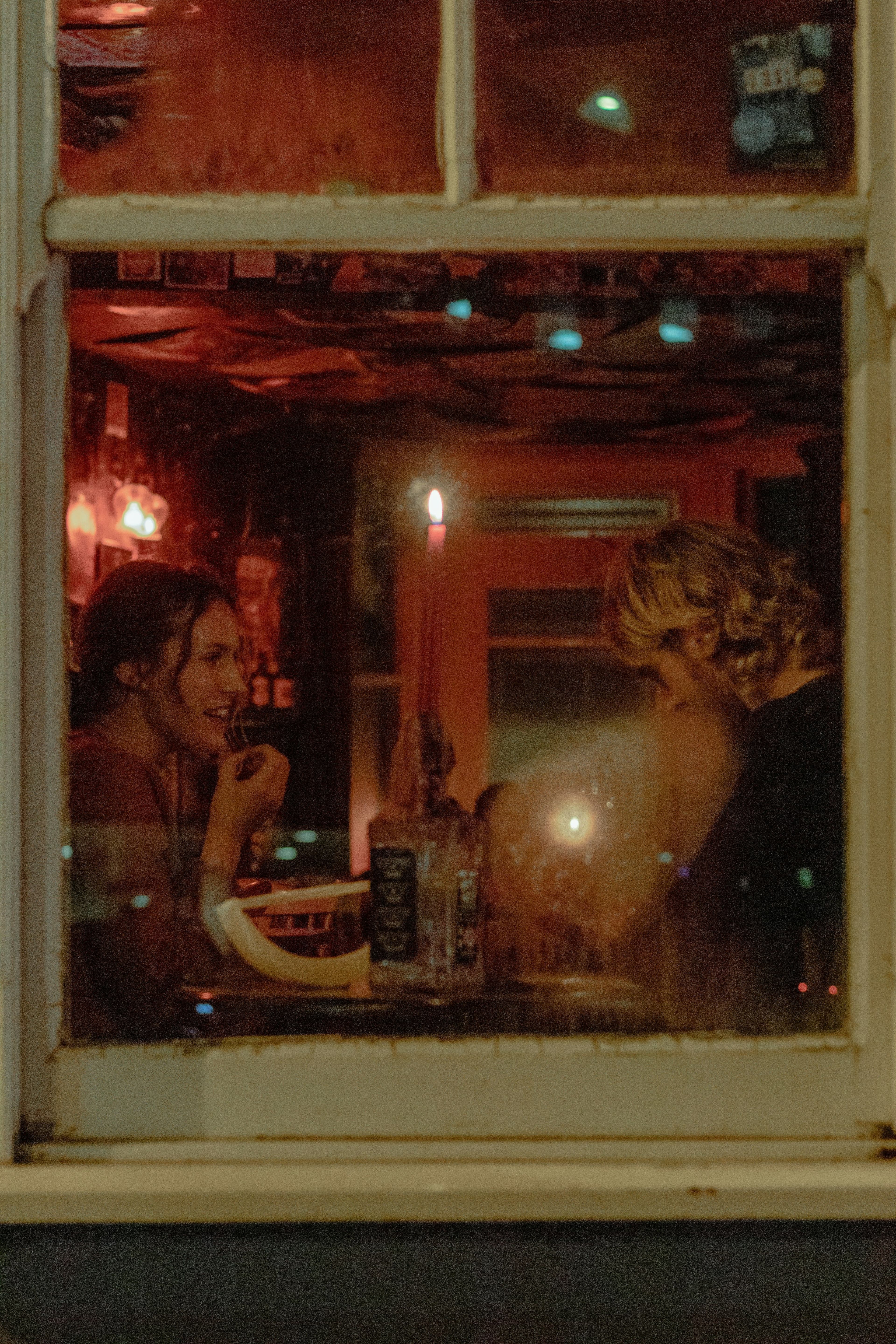 Ein Paar unterhält sich in einer Bar hinter einer Fensterscheibe