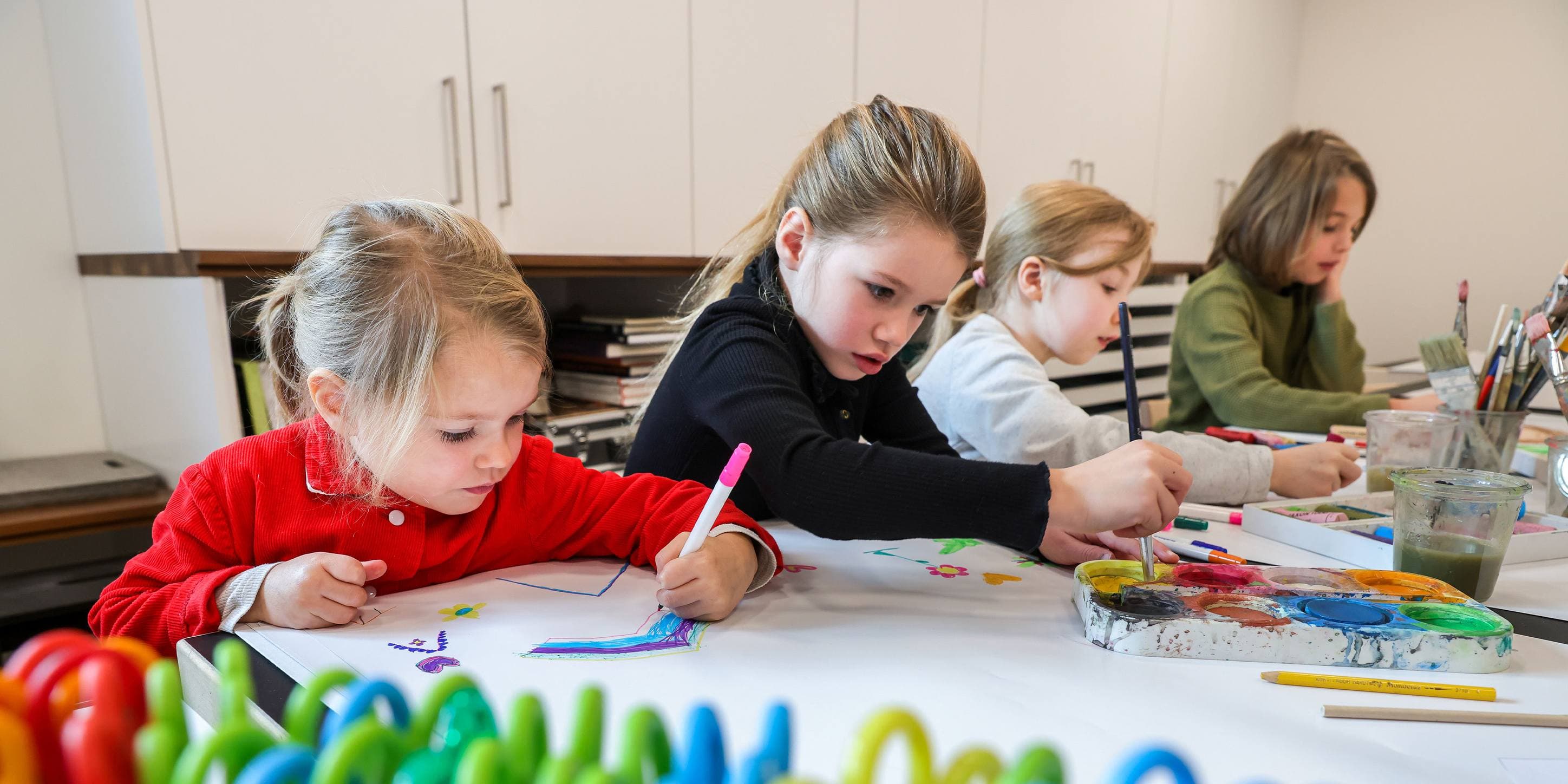 Kinder malen an einem Tisch