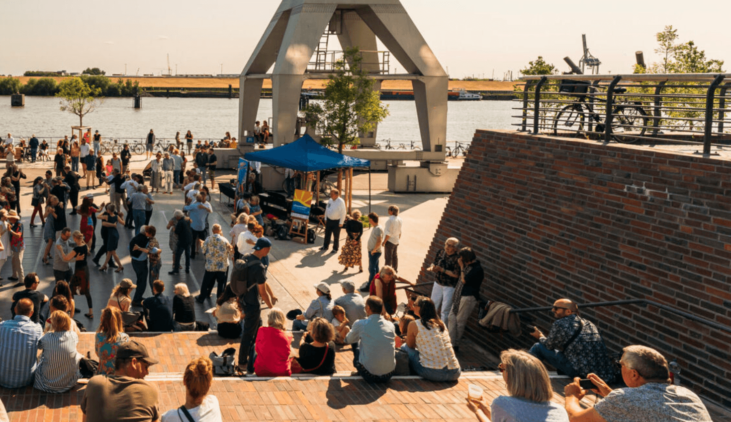 Menschen tanzen Tango auf einem Platz an der Elbe.