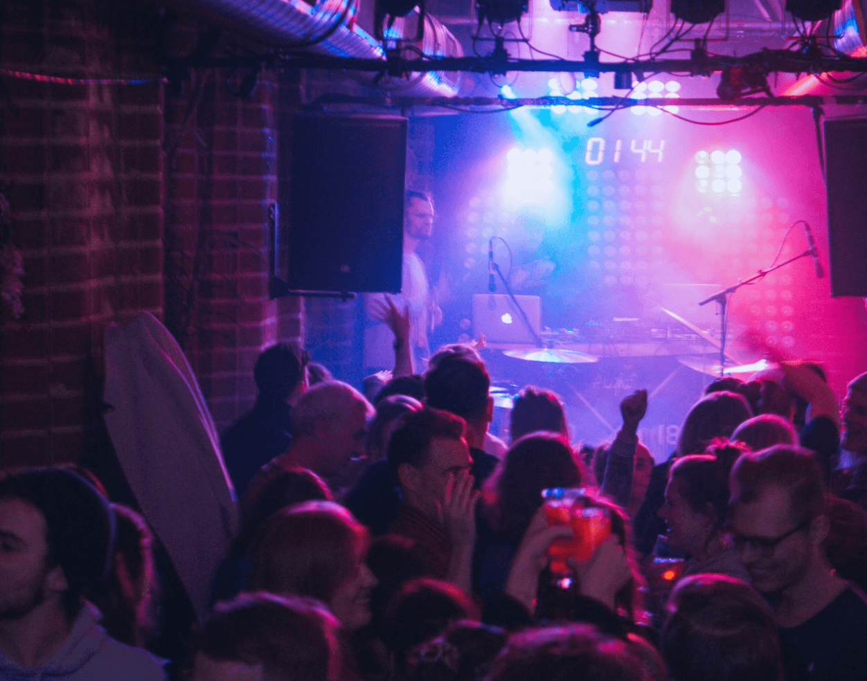 Mehrere Menschen tanzen auf einer Party in einem Club vor einer Bühne