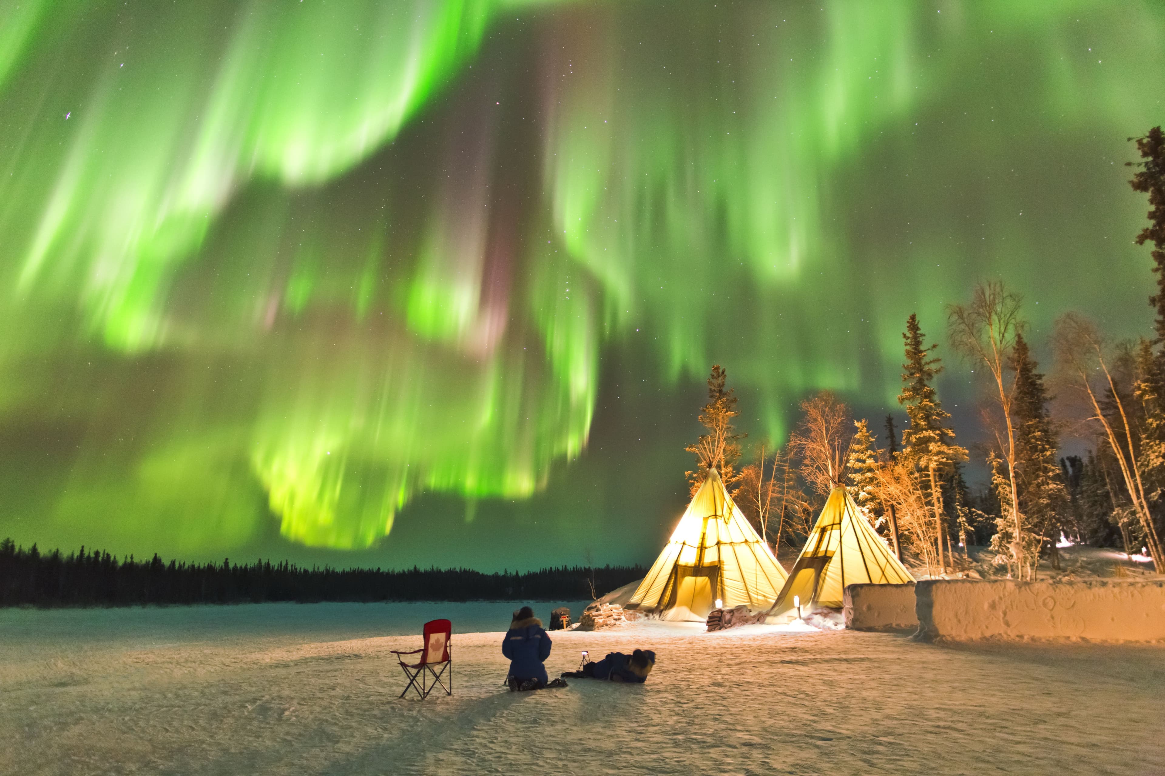Bunte Polarlichter am Himmel über Iglos im Schnee