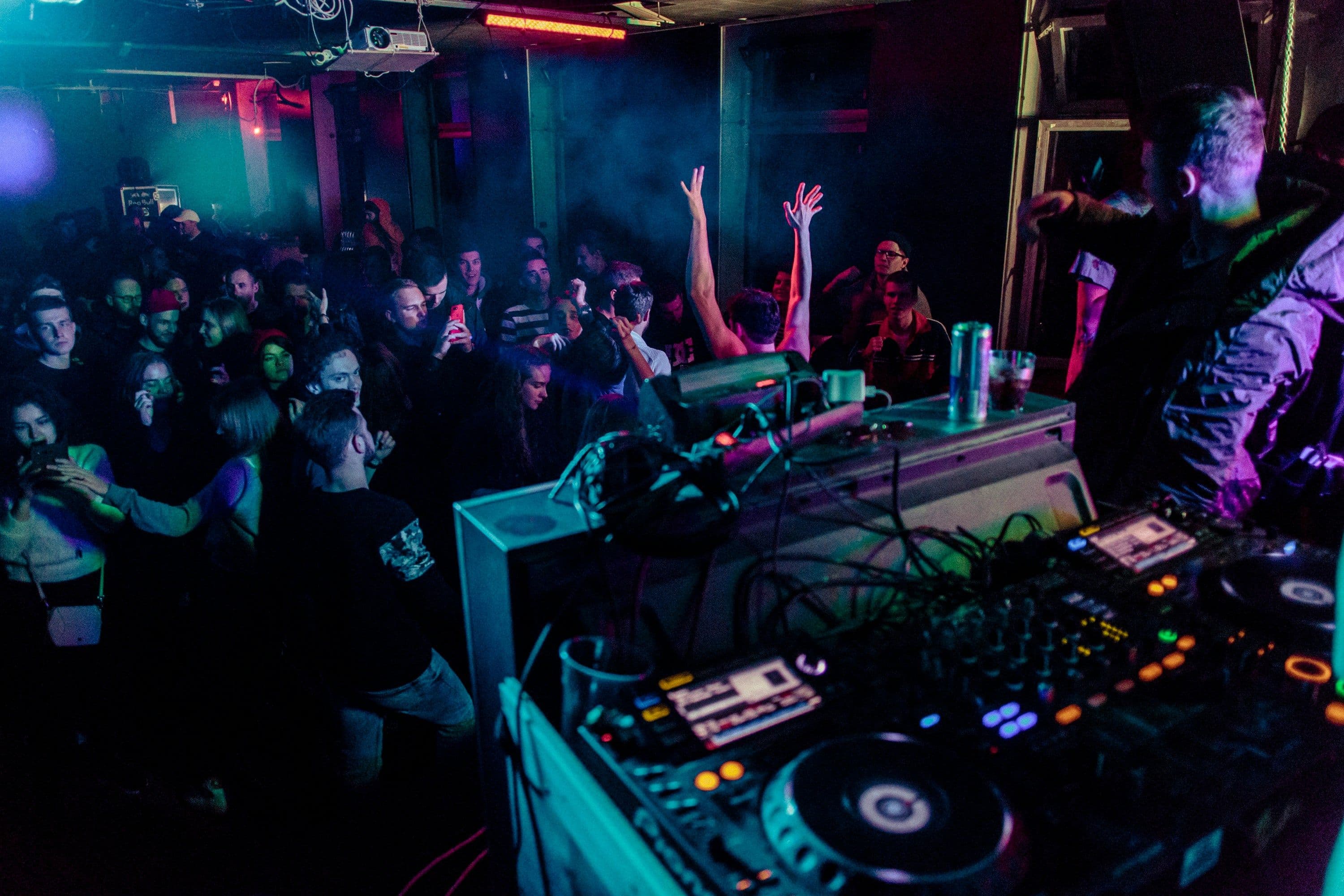 Ein DJ macht in einem Club vor einer Menschenmenge Musik