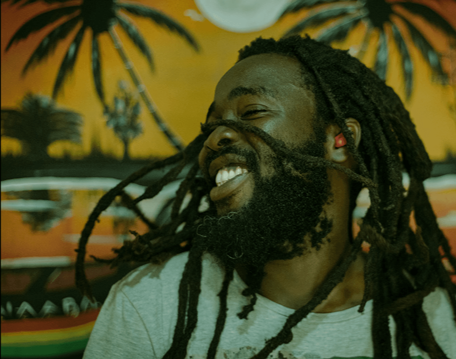 Ein männlicher POC schüttelt lachend seine Dreadlocks
